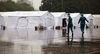 The last batch of medics at the Jianghan makeshift hospital rush to tents for changing clothes amid the rain. ZHANG ZHENG/FOR CHINA DAILY