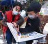 3月18日，志愿者来到杭州市富阳区东洲街道富春江村，给抗疫一线医护人员的孩子章镒宸（右）送来玩具和书籍，并陪他一起看书。 新华社记者徐昱摄