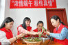 2020年6月24日，在山东省烟台市福山区高疃镇南村，志愿者在端午节主题活动中为老人包粽子。