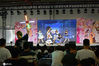 2020年7月10-12日，第十届理想乡动漫展在上海光大会展中心举办。图为舞台上在进行歌舞表演，台下的一位观众拿着荧光棒打call
