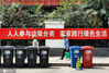2020年5月30日，北京，红色有害垃圾桶、蓝色可回收垃圾桶，黑色其他垃圾桶的分类垃圾桶，行人从”人人参与垃圾分类，家家践行绿色生活”标语前走过。芳芳/IC photo
