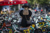  2020年7月24日，中国北京，北京局地气温超40℃，人们出街防晒衣、墨镜、帽子、遮阳伞成必备装备，“全副武装”抵挡烈日。图为一女子站在共享单车旁，准备扫码骑车走。大羽/IC photo
