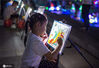 2020年7月4日，小朋友在江苏金湖县城荷花广场夜市绘画区对图上彩。