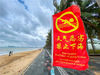 2021年10月19日，海口，假日海滩旅游景区，游客在沙滩上游玩。“天气恶劣 禁止下海”的旗帜标语。