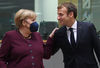 Germany's Chancellor Angela Merkel (L) speaks with France's President Emmanuel Macron on the second day of a European Union (EU) summit at The European Council Building in Brussels on October 22, 2021. 