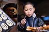 A boy tastes freshly cooked Pansan, a kind of deep-fried dough snack popular among people of the Tu ethnic group during the Lunar New Year holiday, in Baiya village of Weiyuan township, Huzhu Tu autonomous county, Haidong, Northwest China's Qinghai province, Feb 5, 2021. [Photo/Xinhua]
