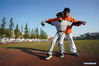 Tseng Chun-an (R) teaches his student during a baseball training session in Xinji Center Primary School in Yizheng, east China's Jiangsu Province, April 9, 2021. Born in a 