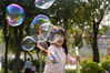 2021年2月21日，广州阳光明媚，春意盎然，恰逢春节后第一个周末，市民选择带小朋友来到户外，乐享周末休闲时光。图为在广州儿童公园草坪上，小朋友在玩泡泡。