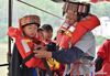 Zhao Shibin (1st R) helps a student wear a life jacket in Huangdong Yao Township of Hezhou City, south China's Guangxi Zhuang Autonomous Region, May 13, 2021. Waiting by the river has been the daily routine of Zhao Shibin for the past 19 years. Zhao, 61, is a ferryman from Huangdong Yao Township in the city of Hezhou, south China's Guangxi Zhuang Autonomous Region. Separated by the Huangdong River, locals who live in the east bank can only be ferried to reach the west bank, where village markets and medical institutions are located. Knowing that the biggest obstacle to people's life was nature itself, Zhao started to ferry residents in 2002 by pulling the iron-clad boat with a rope through the 105-meter waterway. He has therefore gained the nickname 