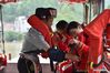 Zhao Shibin (L) helps a student wear a life jacket in Huangdong Yao Township of Hezhou City, south China's Guangxi Zhuang Autonomous Region, May 13, 2021. Waiting by the river has been the daily routine of Zhao Shibin for the past 19 years. Zhao, 61, is a ferryman from Huangdong Yao Township in the city of Hezhou, south China's Guangxi Zhuang Autonomous Region. Separated by the Huangdong River, locals who live in the east bank can only be ferried to reach the west bank, where village markets and medical institutions are located. Knowing that the biggest obstacle to people's life was nature itself, Zhao started to ferry residents in 2002 by pulling the iron-clad boat with a rope through the 105-meter waterway. He has therefore gained the nickname 