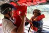 Zhao Shibin (R) helps a villager wear a life jacket in Huangdong Yao Township of Hezhou City, south China's Guangxi Zhuang Autonomous Region, May 13, 2021. Waiting by the river has been the daily routine of Zhao Shibin for the past 19 years. Zhao, 61, is a ferryman from Huangdong Yao Township in the city of Hezhou, south China's Guangxi Zhuang Autonomous Region. Separated by the Huangdong River, locals who live in the east bank can only be ferried to reach the west bank, where village markets and medical institutions are located. Knowing that the biggest obstacle to people's life was nature itself, Zhao started to ferry residents in 2002 by pulling the iron-clad boat with a rope through the 105-meter waterway. He has therefore gained the nickname 