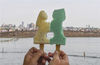 2021年5月1日，浙江杭州，游客在西湖边以断桥为背景展示许仙和白素贞断桥相会的创意雪糕。浙江杭州以西湖文化故事推出的文创雪糕，受到民众喜爱。