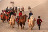 2021年5月1日，甘肃酒泉，在敦煌市鸣沙山月牙泉景区，身穿“胡服”的驼户为游客提供牵骆驼服务。张晓亮/视觉中国