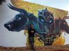 An artist poses with a mural in Guanzhong village, Yunnan province. [Photo provided to chinadaily.com.cn]