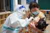 Wang Yu (L) takes a swab sample from a child for COVID-19 test at a testing site of Longxi Community in Jiangning District of Nanjing, capital of east China's Jiangsu Province, July 24, 2021. A second round of COVID-19 nucleic acid test was launched Saturday night in Jiangning District of Nanjing. Wang Yu, a nurse from Dongshan Community Hospital in Jiangning District, was racing against time in epidemic battle on Saturday night. Wang, along with other medical workers and community workers, has been busy conducting nucleic acid tests for the residents until late night. (Xinhua/Li Bo)