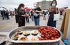 A woman wearing a face mask takes a photo of cooked dish during the 2021 Asialicious Carnival in Toronto, Canada, on Sept. 12, 2021. Kicking off on Friday, this three-day event showcased diverse Asian culture and heritage through a variety of performances and ethnic foods. (Photo by Zou Zheng/Xinhua)