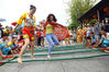 A tourist, right, joins a performer for a bamboo dance at the Nanshan Cultural Tourism Zone in Sanya, Hainan province on April 14, 2021. [Photo by Chen Wenwu/for China Daily]