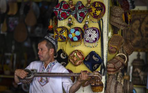 图为在新疆喀什古城景区里,工作人员弹奏民族乐器"热瓦普".新华社