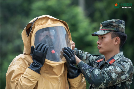 武警官兵相互協同穿戴防護服.