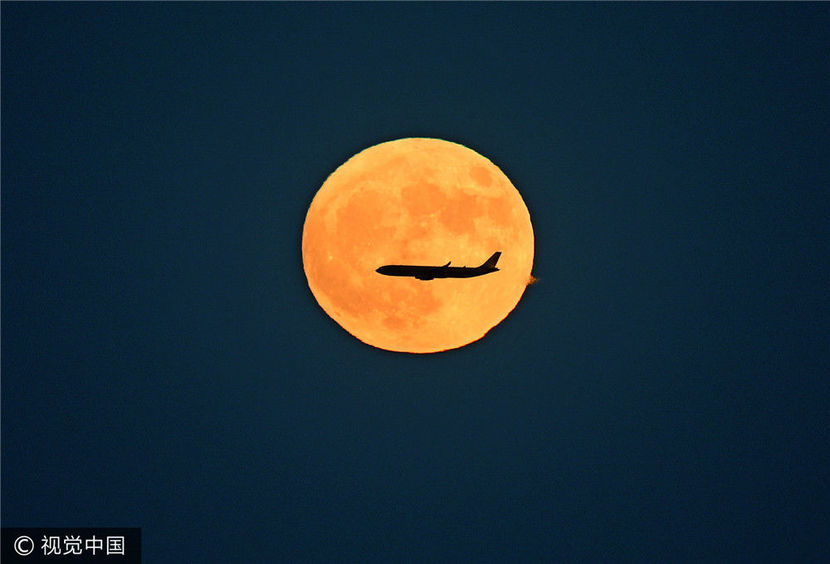 2016年11月14日,北京,一轮特大金黄色月亮从北京东方升起,一架民航