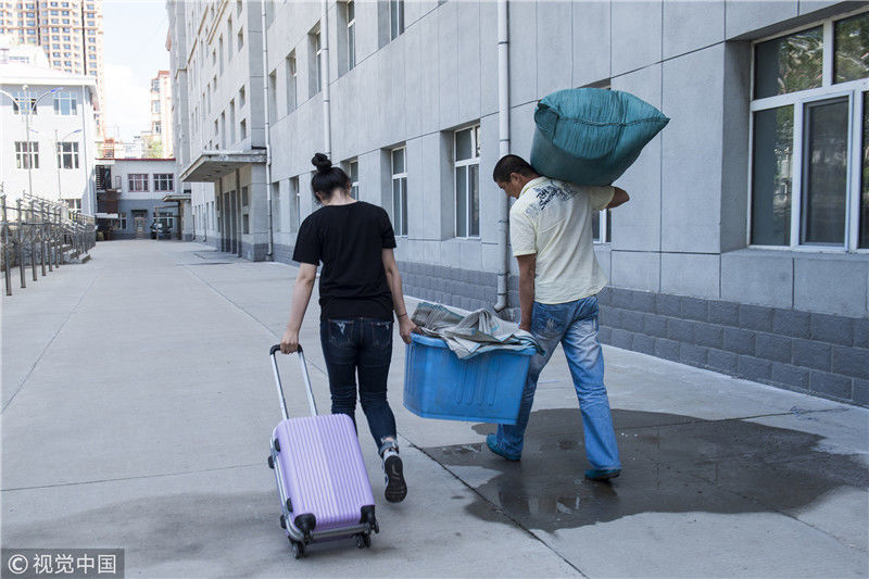 黑龙江省示范高中密山一中宿舍楼前,一位父亲臂膀扛着女儿的行礼,和