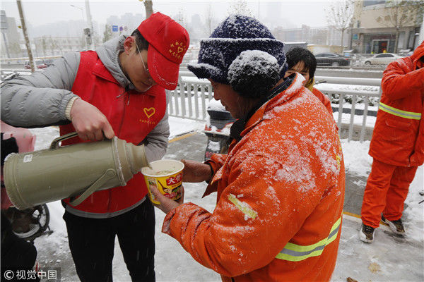 上,给正在冒雪清理路面的环卫工们泡方便面吃,并接替环卫工干一会儿活
