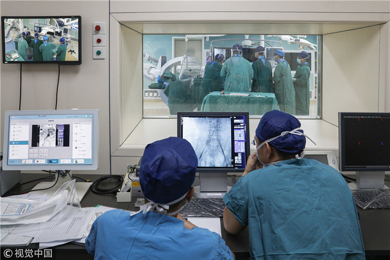 手术室内几名医师正通过高科技微创医疗设备观察患者病情进行手术治疗