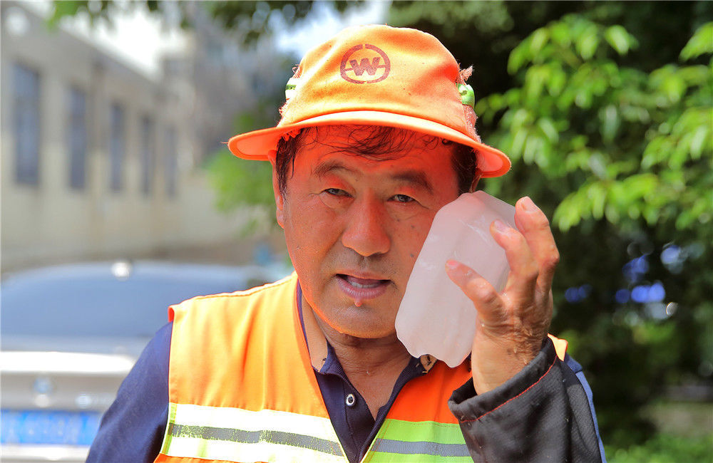 2019年7月23日,江苏连云港,环卫工人用冰块给自己降温