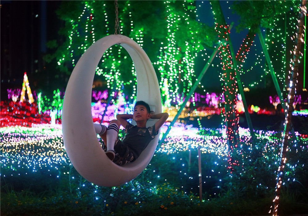 2019年7月7日,福建福州,一个小朋友躺在秋千上欣赏灯展.