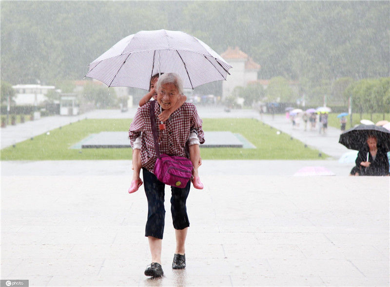 2017年06月10日,江苏省南京市,瓢泼大雨中,一位老奶奶背着孩子冒雨到