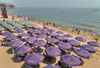 2022年6月18日，在江苏省连云港连岛大沙湾游乐场沙滩上，人们在遮阳伞下纳凉。