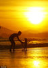 2022年6月19日，海南三亚，游客在三亚湾夕阳下游玩。