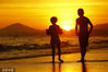 2022年6月19日，海南三亚，游客在三亚湾夕阳下游玩。