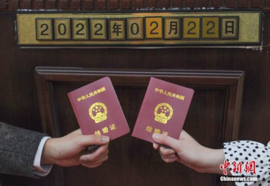 资料图：一对新人拿结婚证和日期数字拍照。 中新社记者 王刚 摄