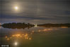 2022年8月12日，海南琼海，人们在万泉河中投放河灯，与超级月亮交相辉映。