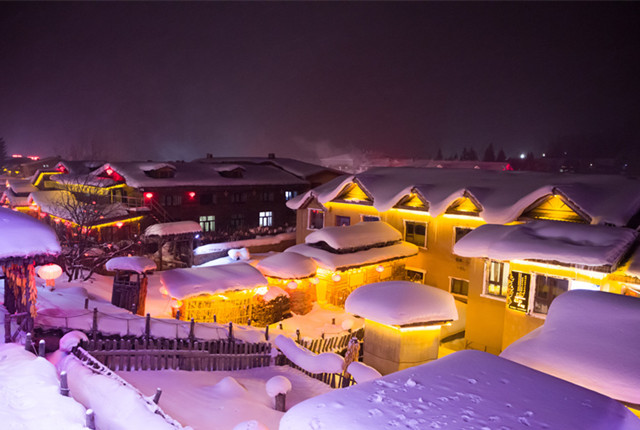 哈尔滨雪乡风景区灯光璀璨 积雪如棉被覆盖建筑