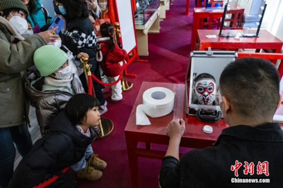 图为小朋友观看京剧演员化妆扮相。 中新社记者 侯宇 摄