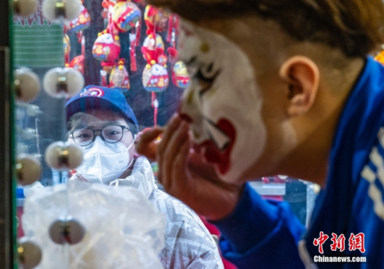 图为户外途经的一名小朋友被室内正在化妆扮相的京剧演员吸引。 中新社记者 侯宇 摄