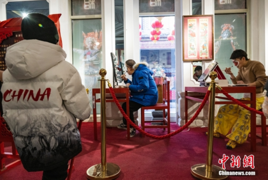 图为小朋友观看京剧演员化妆扮相。 中新社记者 侯宇 摄